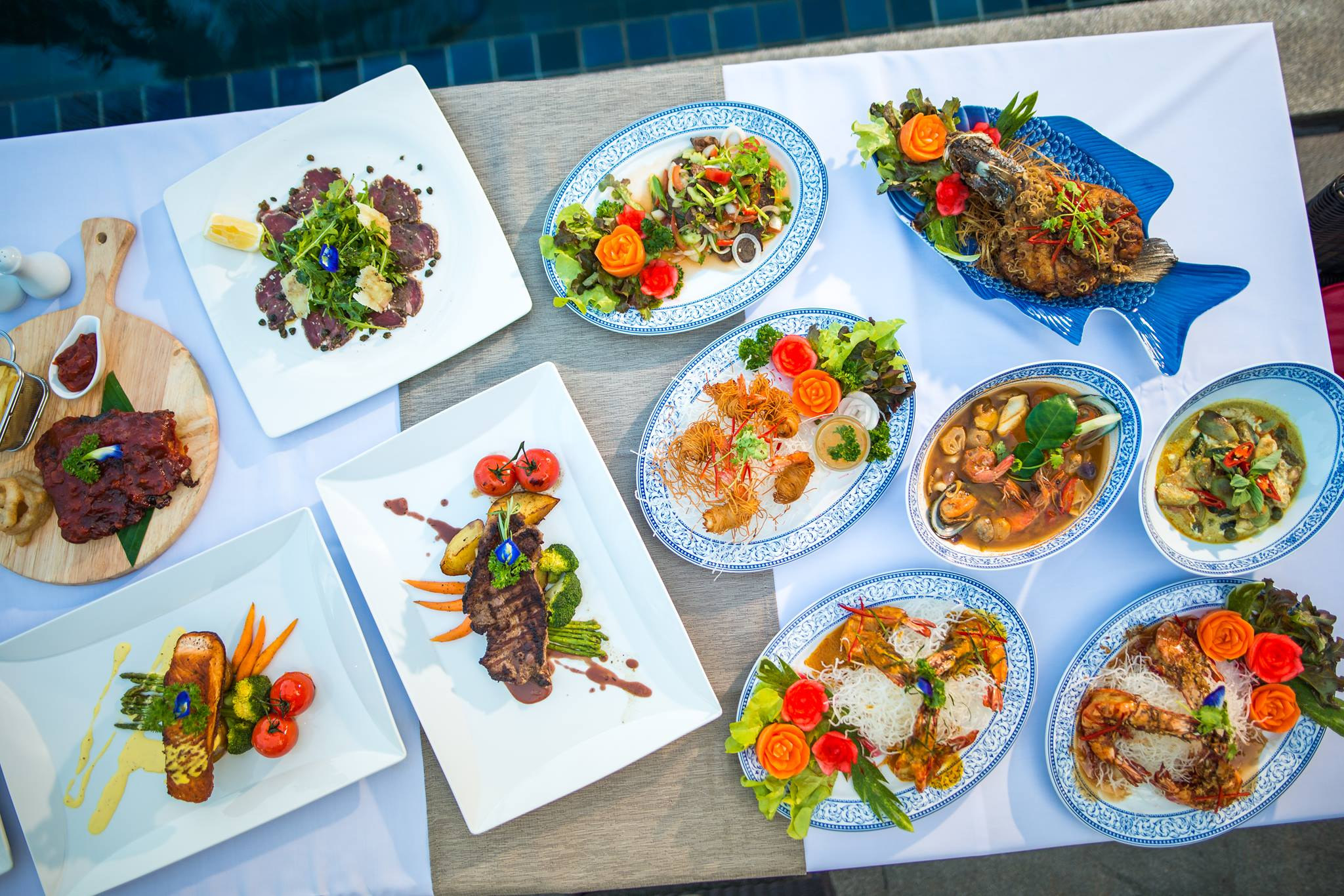 Southern Thai dishes from the RICE kitchen laid out on a table by the pool
